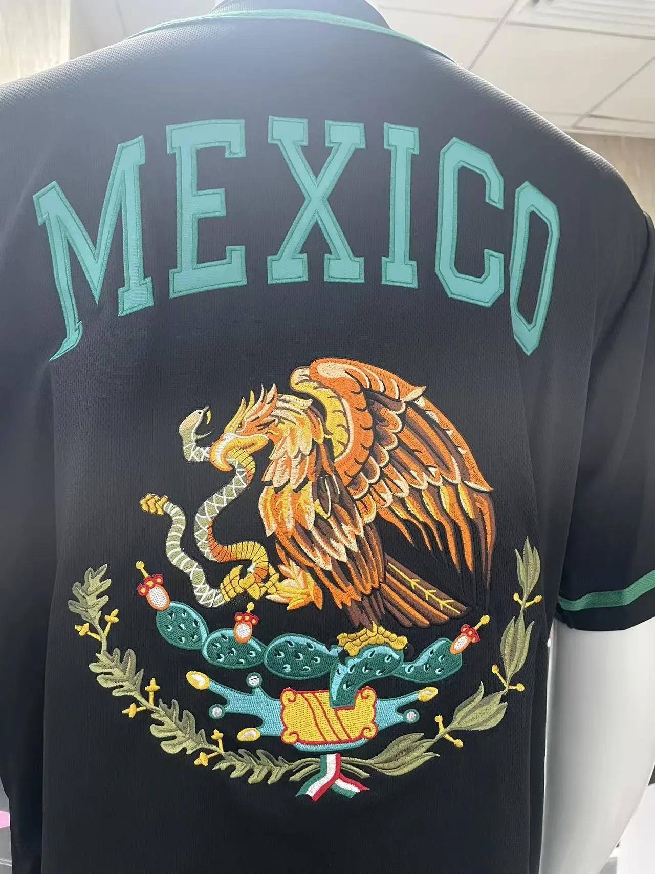 Back of black baseball jersey with embroidered Mexican coat of arms eagle crest