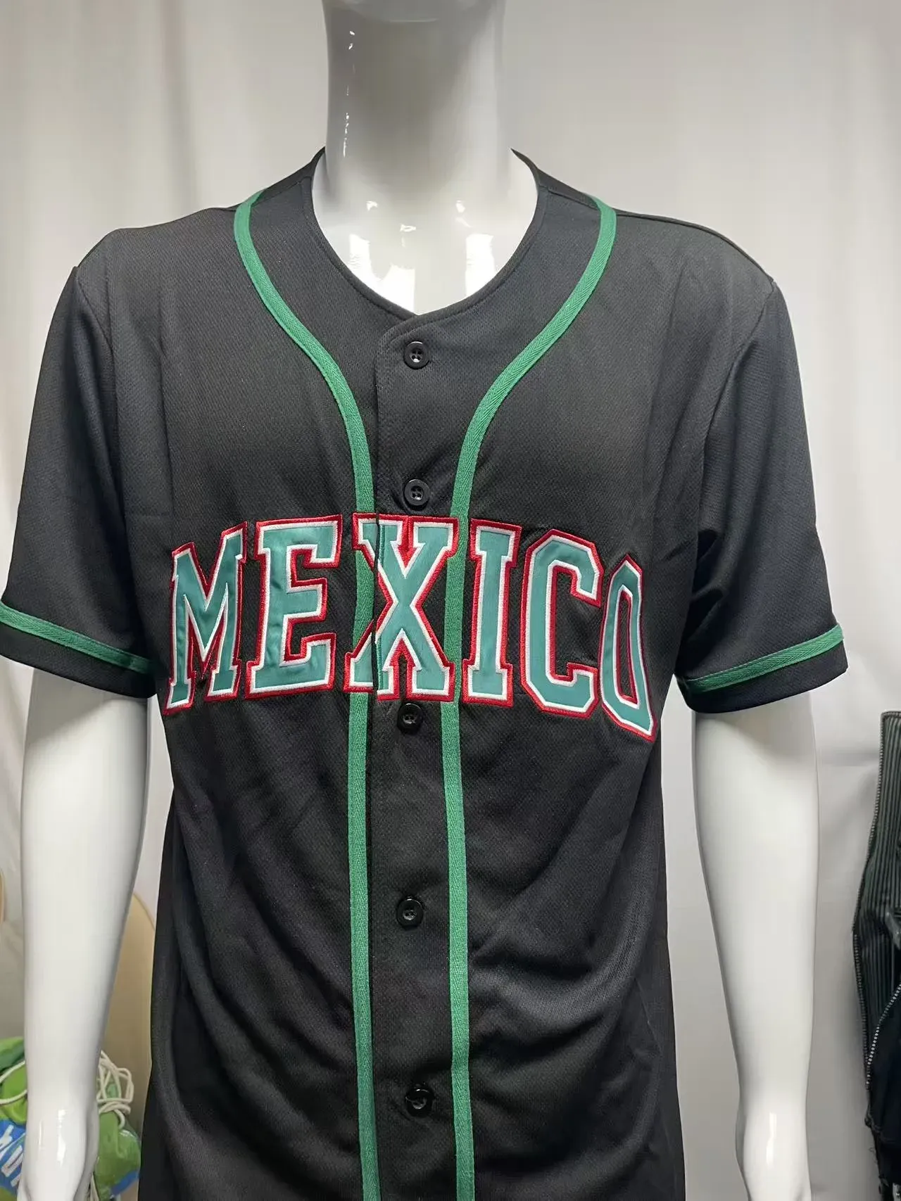 Custom embroidered black baseball jersey with MEXICO tackle twill lettering and green trim