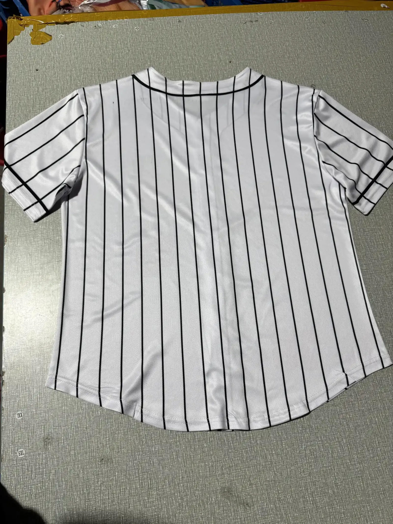 White baseball jersey with black pinstripes showing mesh fabric texture