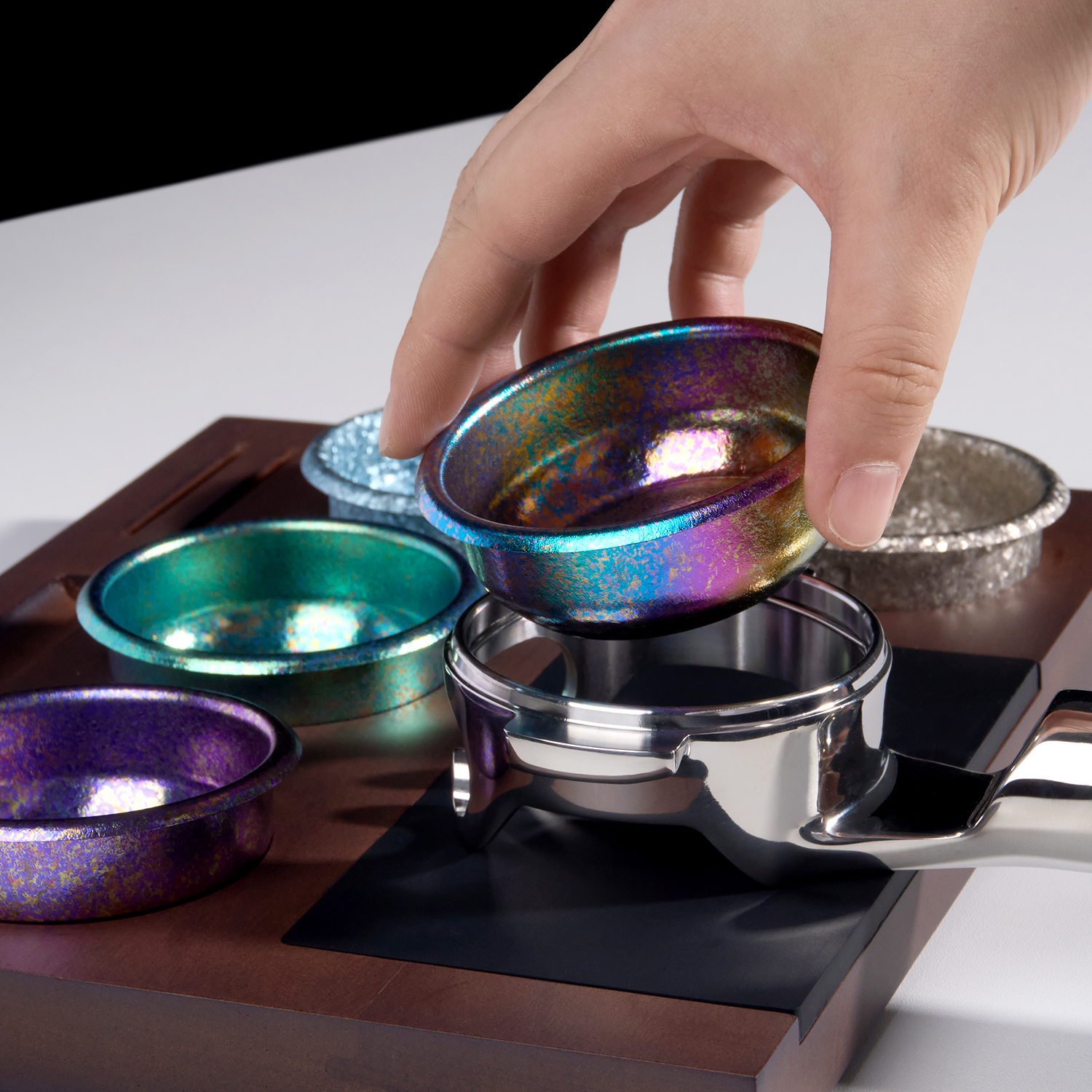 Colored titanium espresso baskets beside a portafilter
