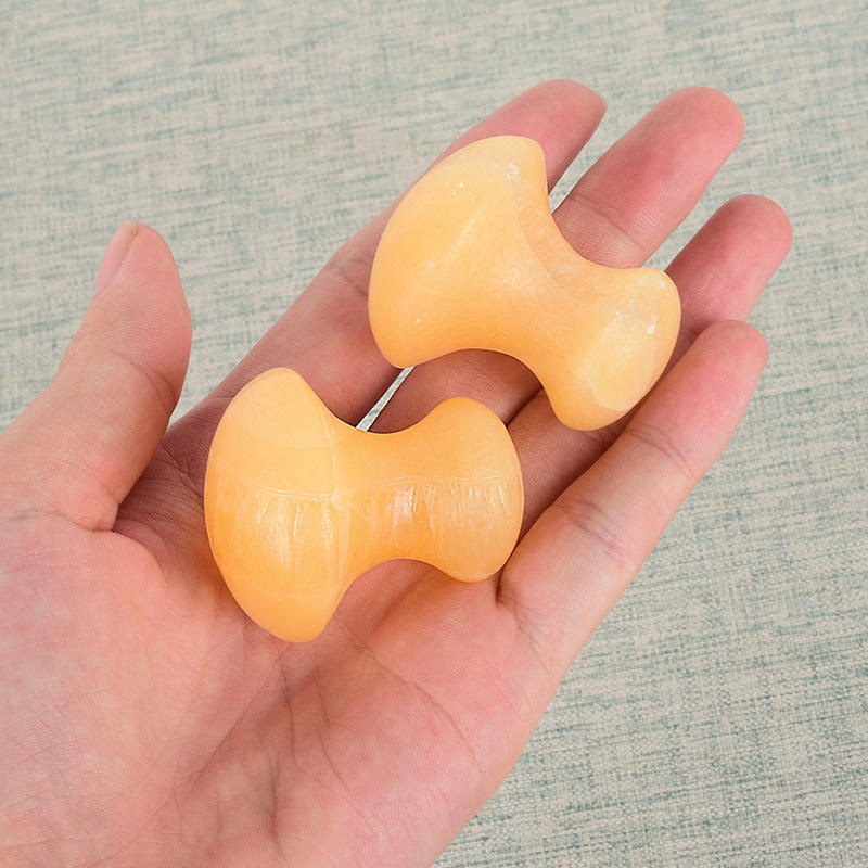 Yellow jade mushroom gua sha massage stones in hand