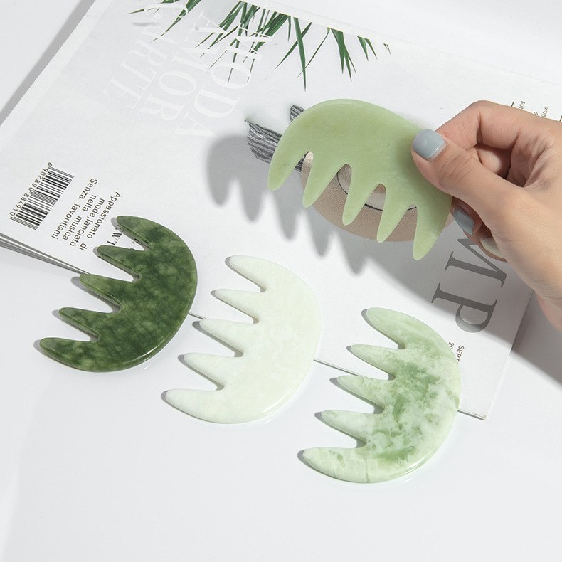 Hand holding the five-tooth jade comb over a set