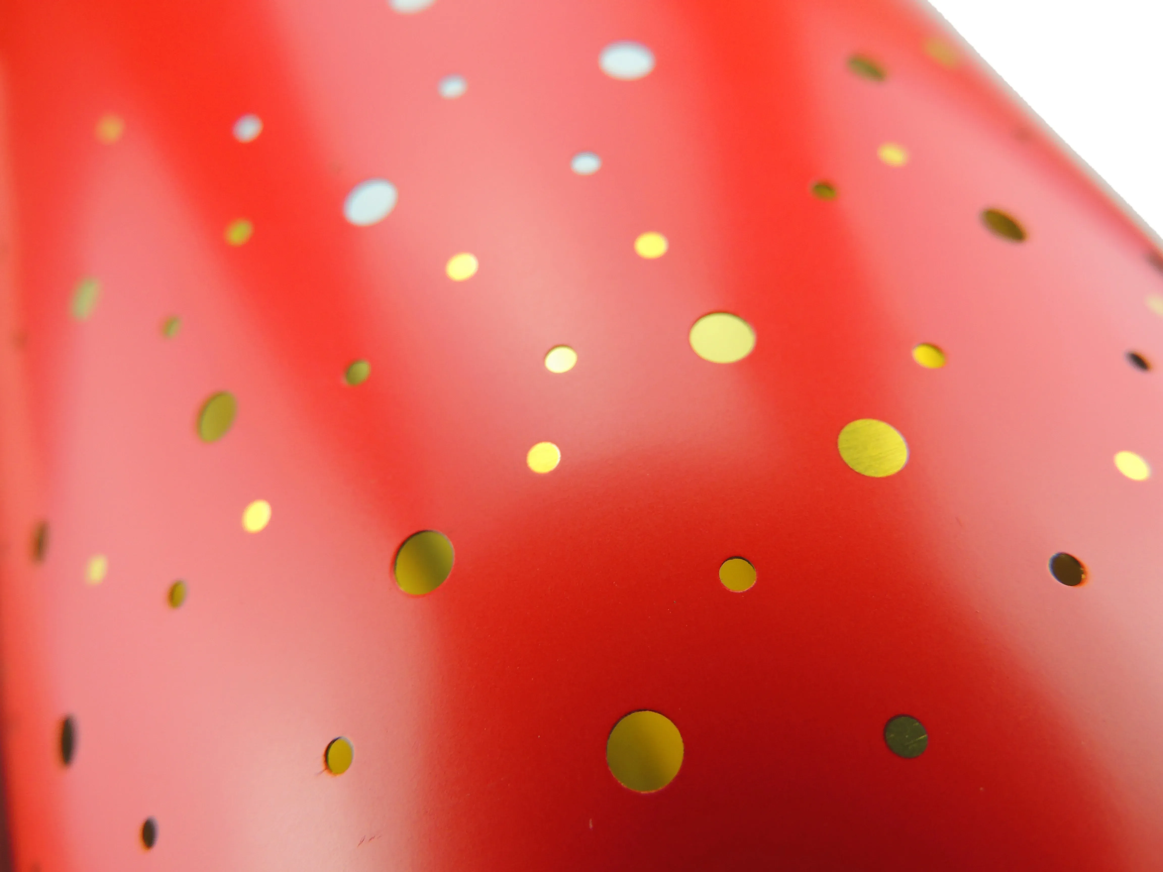 Detail of the candle tin surface with gold and black dots scattered on red