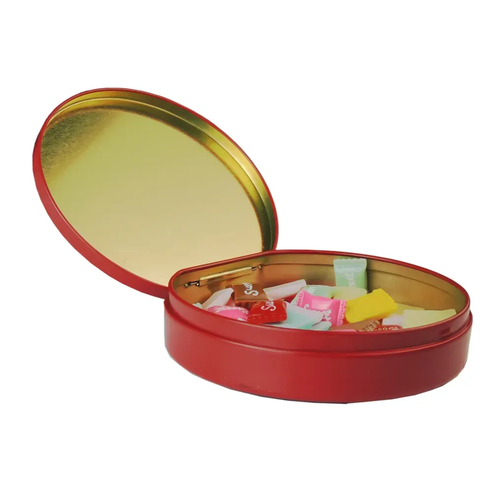 Round red candy tin with the hinged lid open, showing wrapped sweets in a gold-lacquered interior, on a white background