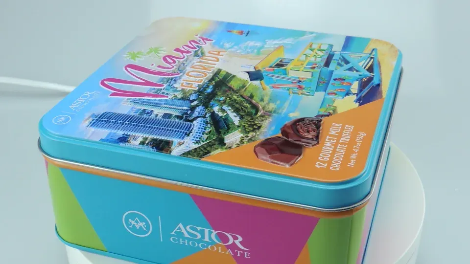 Square tin printed with a colorful beach design, shown at an angle