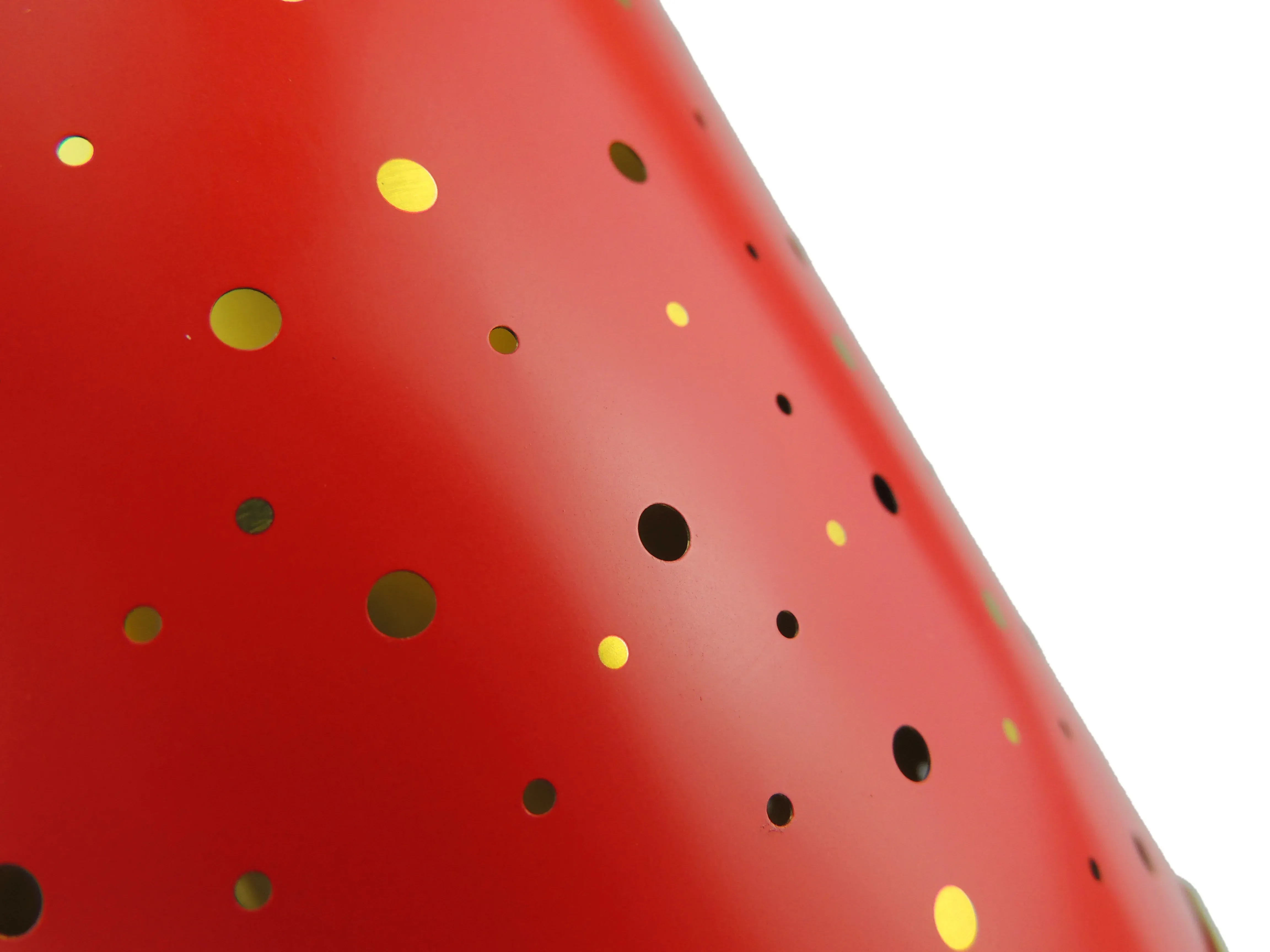 Close-up of the candle tin print: gold and black dots on a red background