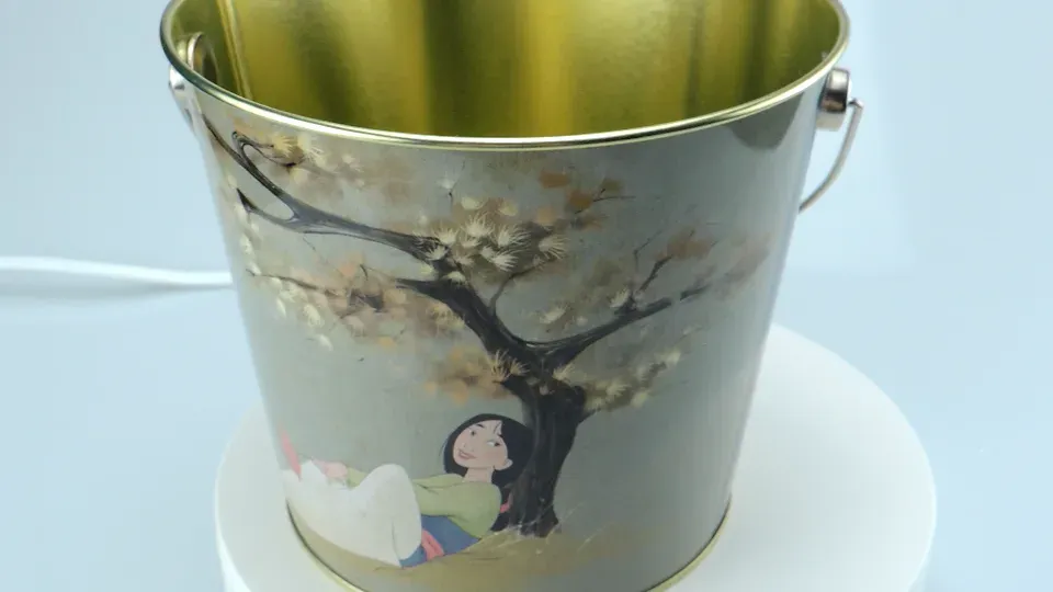 Tin bucket printed with blossom branches, seen at an angle from above