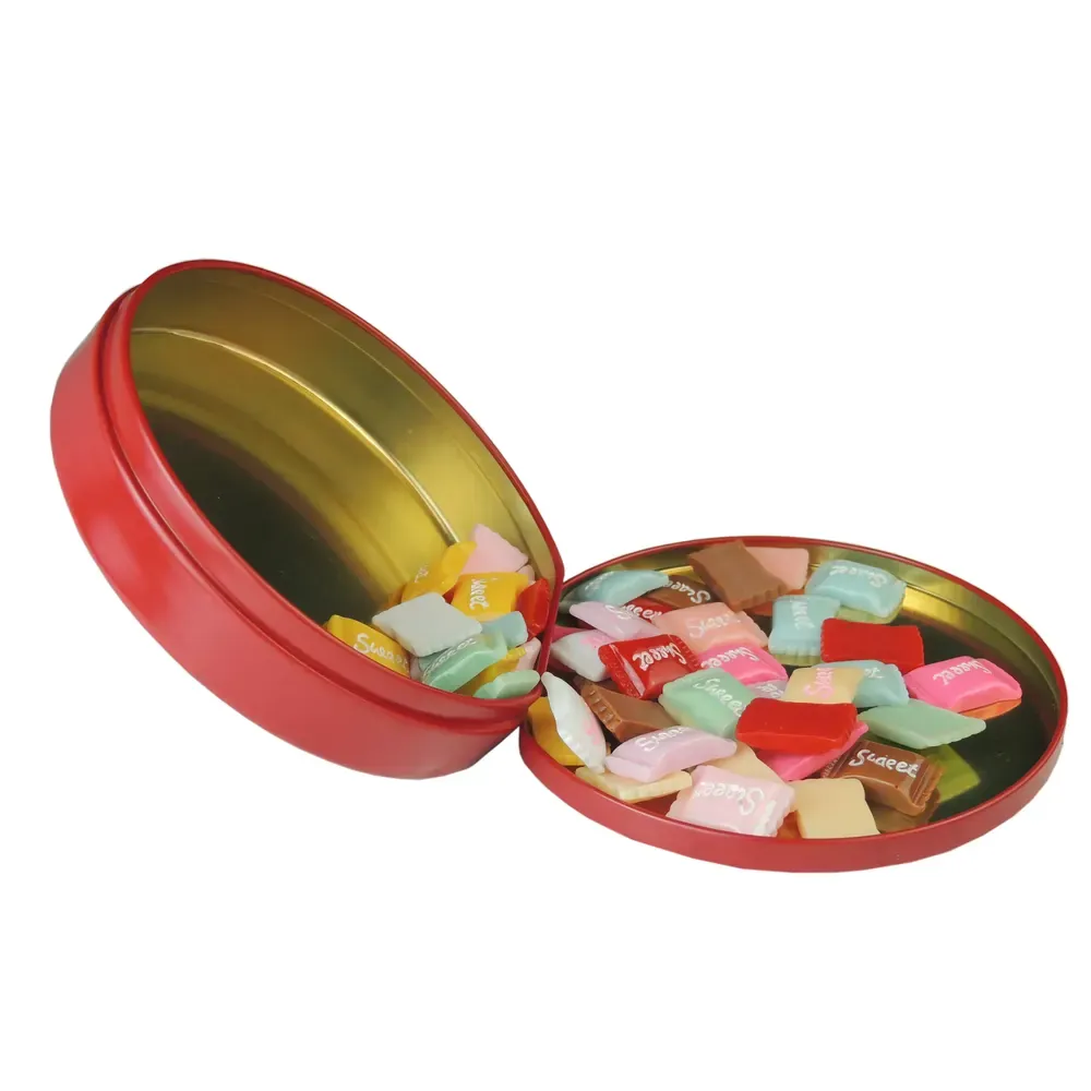 Red candy tin with the lid folded open beside the body filled with wrapped sweets, on a white background