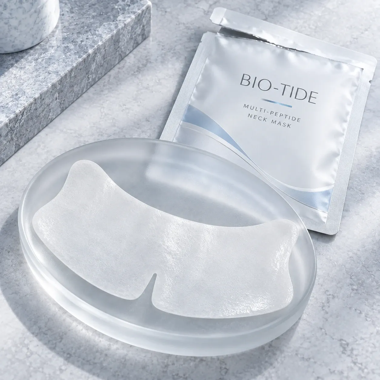 White contour neck mask sheet presented beside a BIO-TIDE sachet