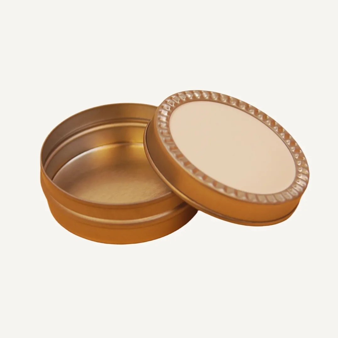 Open round gold tin box with decorative ring lid