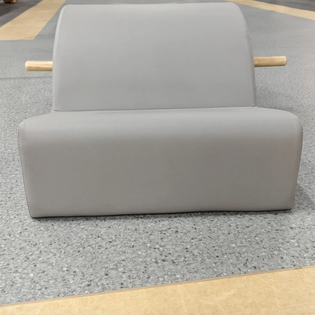 Front view of the grey upholstered Pilates spine corrector showing the arc, the flat pad and the wooden bars at both sides