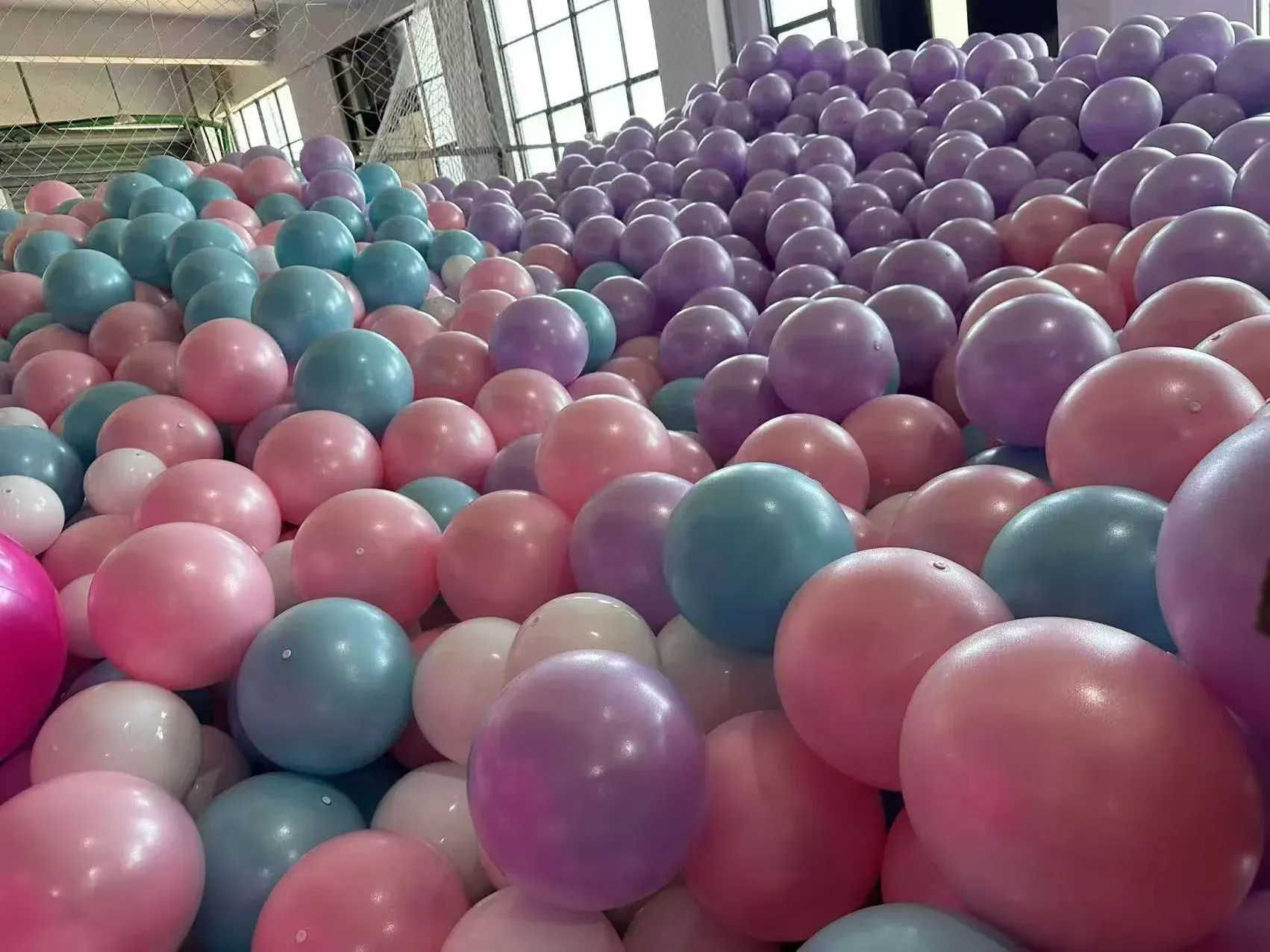 Bulk piles of small yoga balls in pink, green, purple, blue and silver at the factory