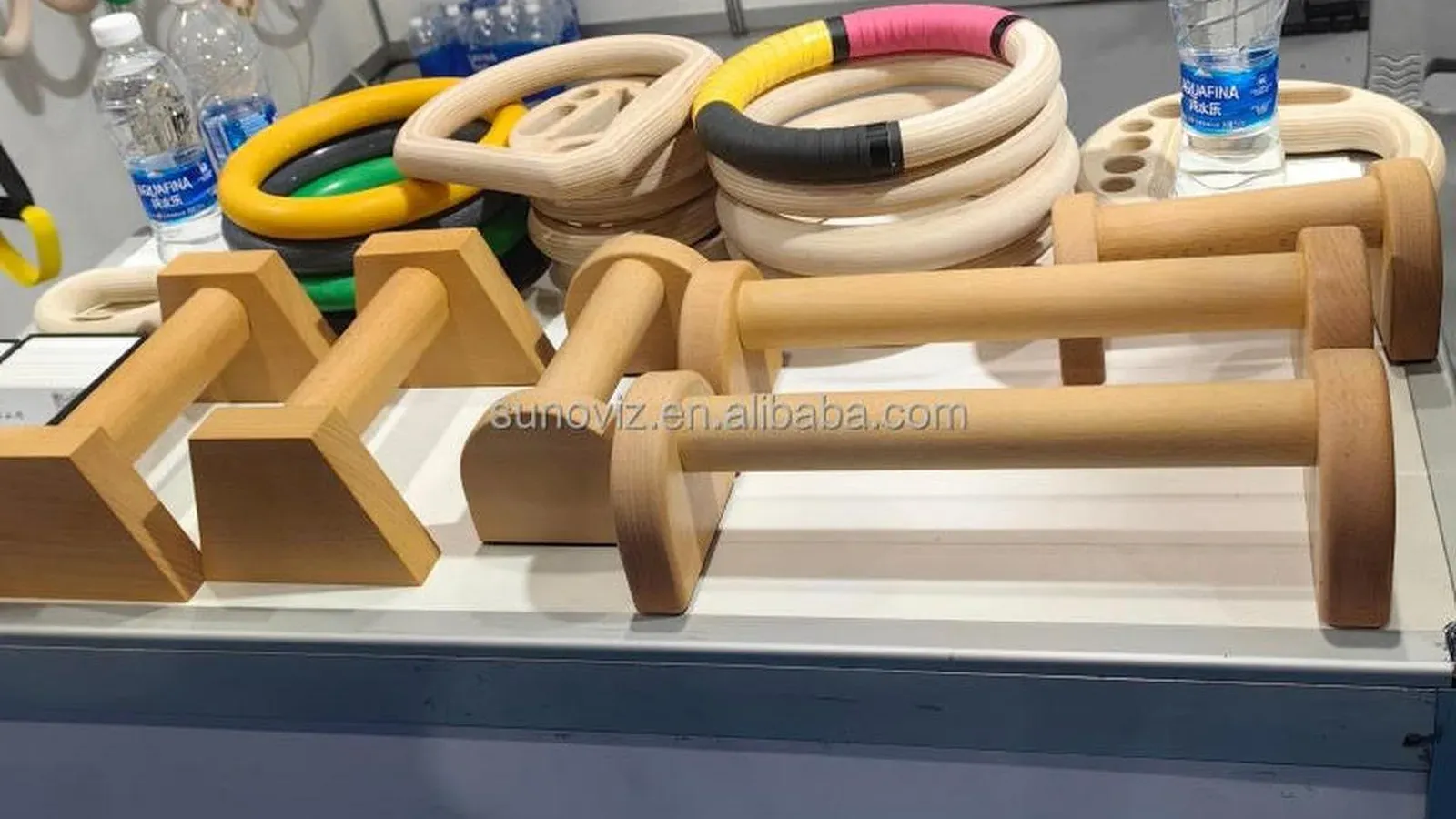 Solid light-toned beech wood push-up stands on a showroom display, with two angular block stands on the left and round-handle push-up bars across the centre and right