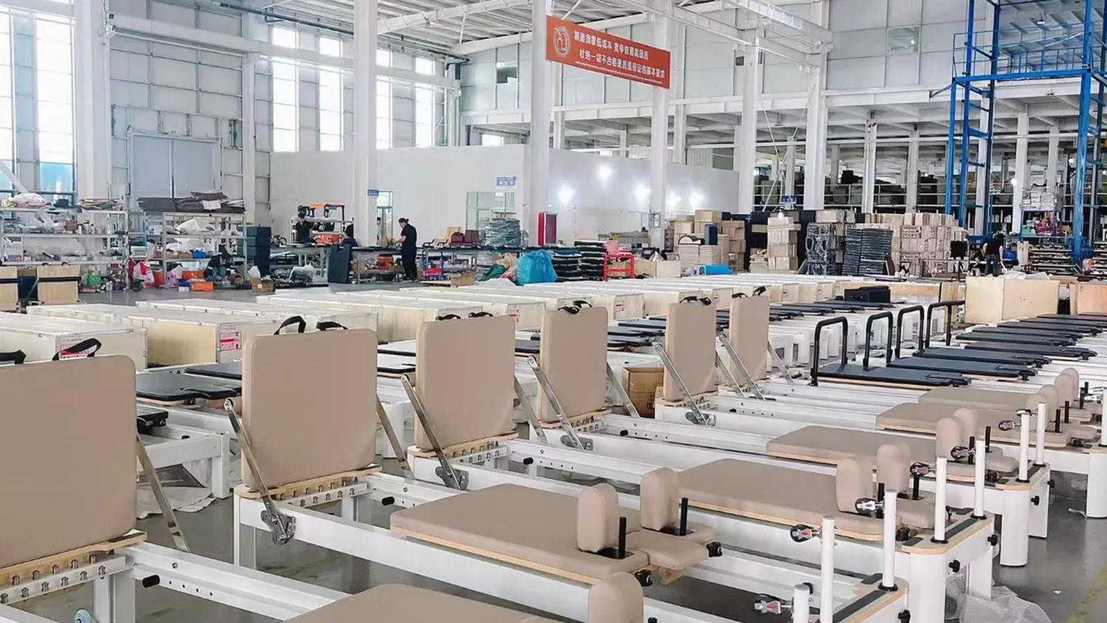 Rows of light coffee leather Pilates reformers in a bright factory workshop