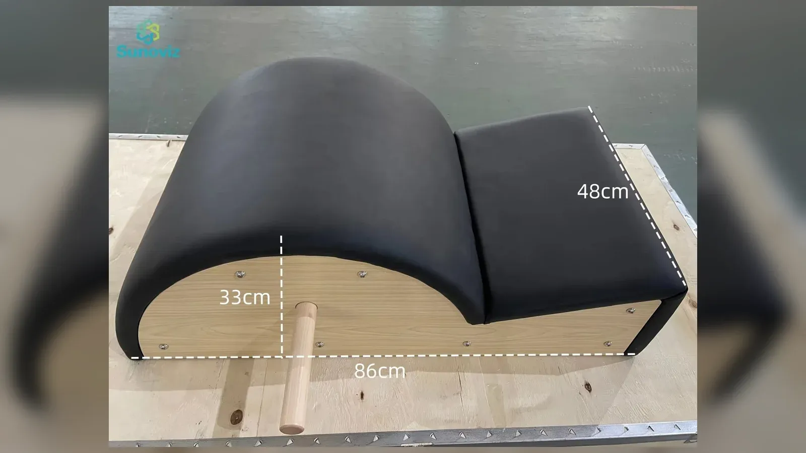 A black upholstered Pilates spine corrector on a maple wood frame, with 86cm, 48cm and 33cm measurements marked on the photo