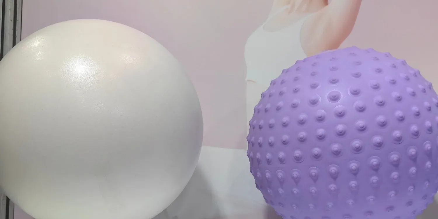 Small yoga balls in white and a textured purple finish with raised knobs