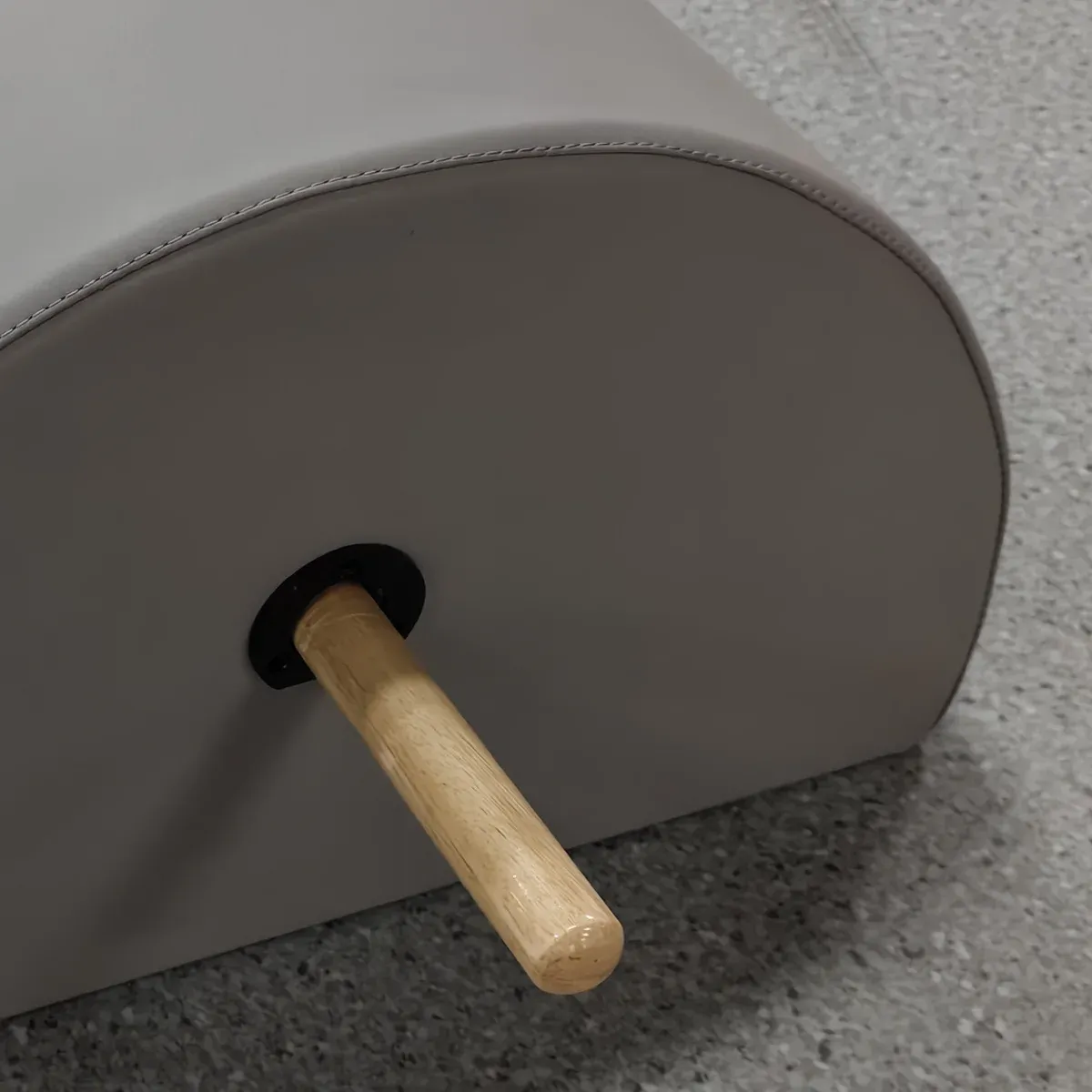 Close-up of the wooden bar where it leaves the grey end face of the Pilates spine corrector