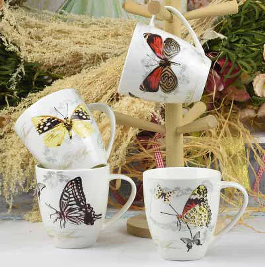 Four white ceramic mugs decorated with large butterfly artwork in yellow, red, black and earth tones