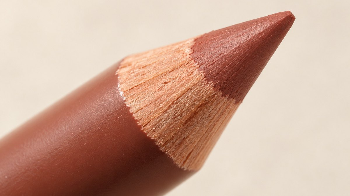 Close-up of a cosmetic pencil being sharpened, showing the wood barrel and exposed color core