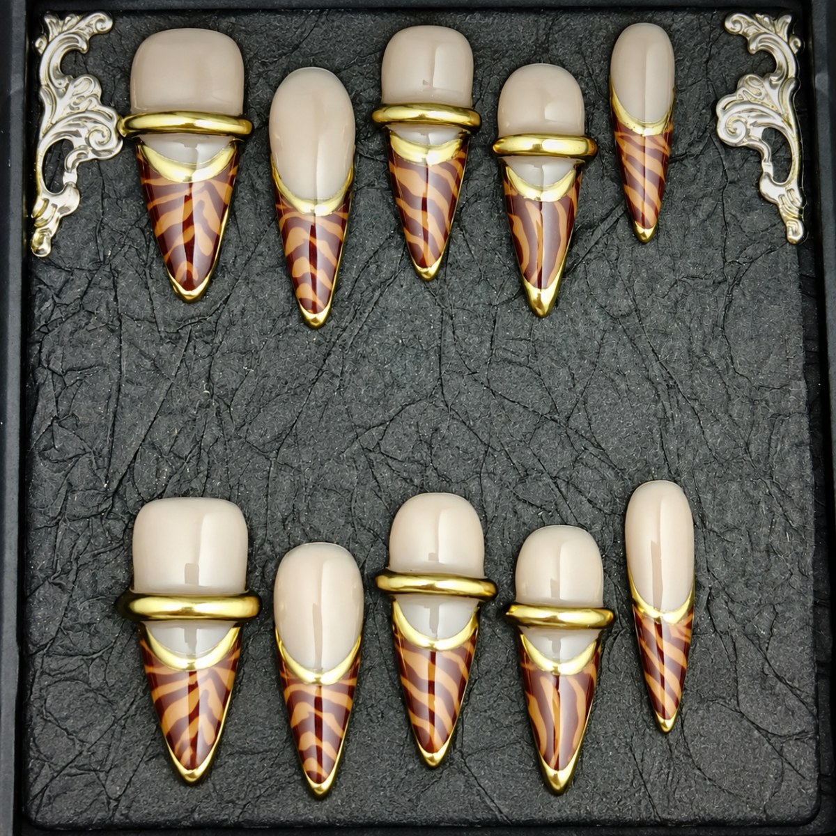 Nude stiletto press-on nails with burgundy tortoiseshell tips and gold edging