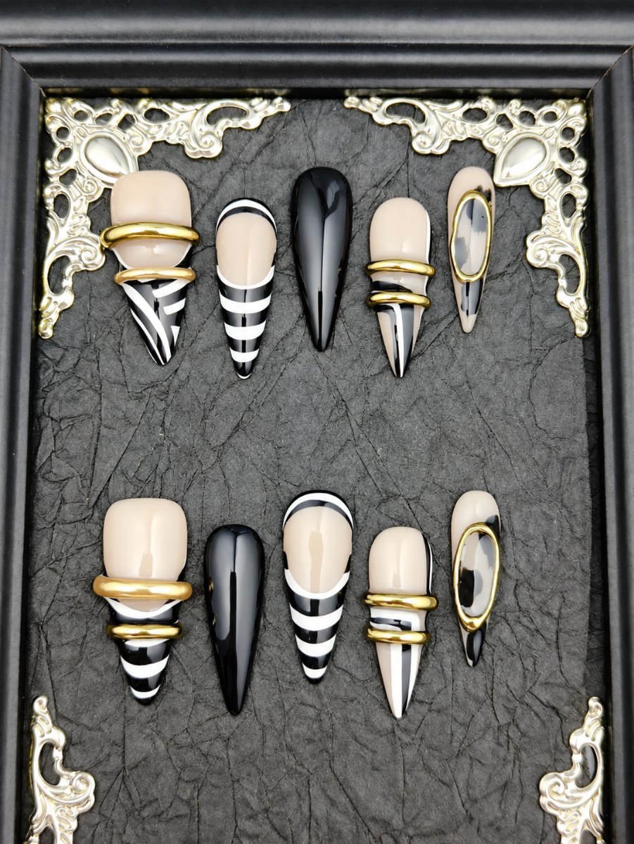 Black and white striped stiletto press-on nails with gold ring charms