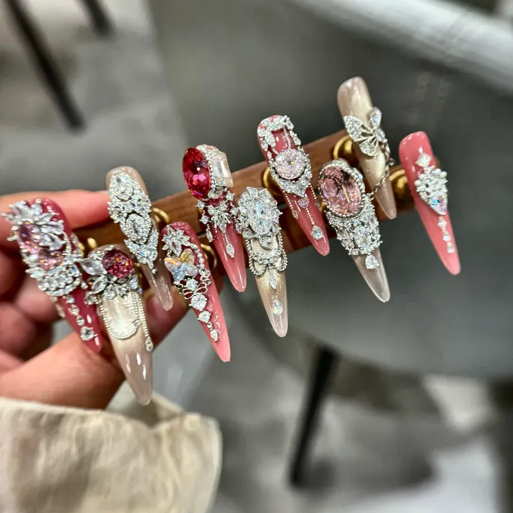 Extra long stiletto press-on nails showing crystal settings, silver filigree and rhinestone drape