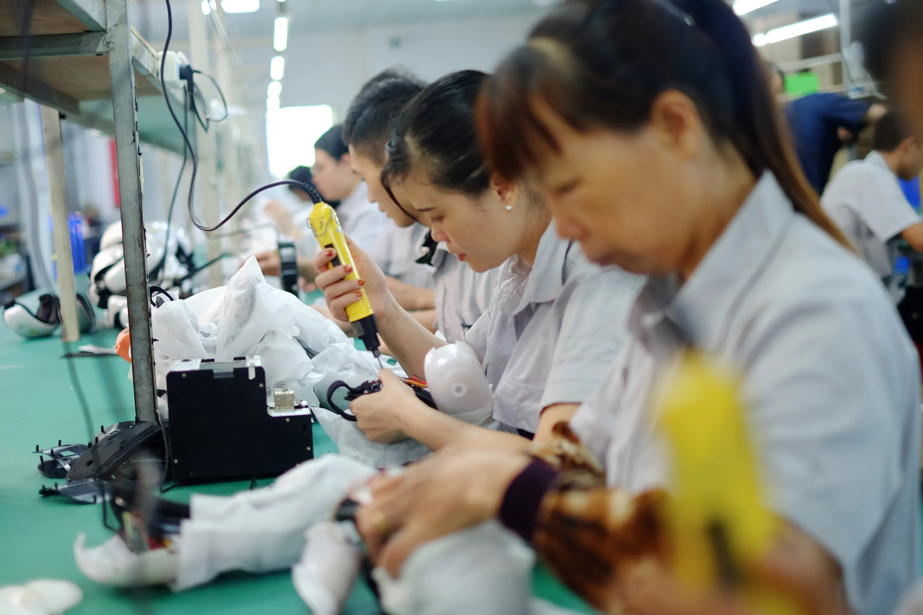 Worker assembling massage device with screwdriver at ZonyouTech production line