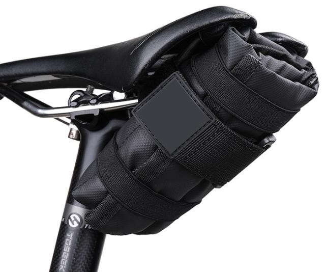 Black KY067 triangular saddle-under bag opened to show separate pockets holding a screwdriver, wrench, tire levers and spare tubes