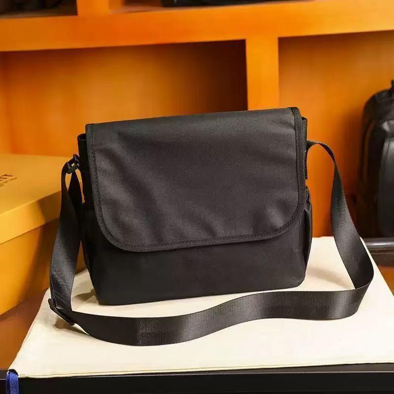 Black musette-style messenger bag with a large rectangular flap, magnetic buckle and adjustable shoulder strap