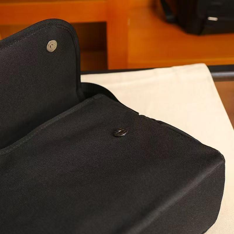 Close-up of the black musette bag flap with the round magnetic stud and snap closure