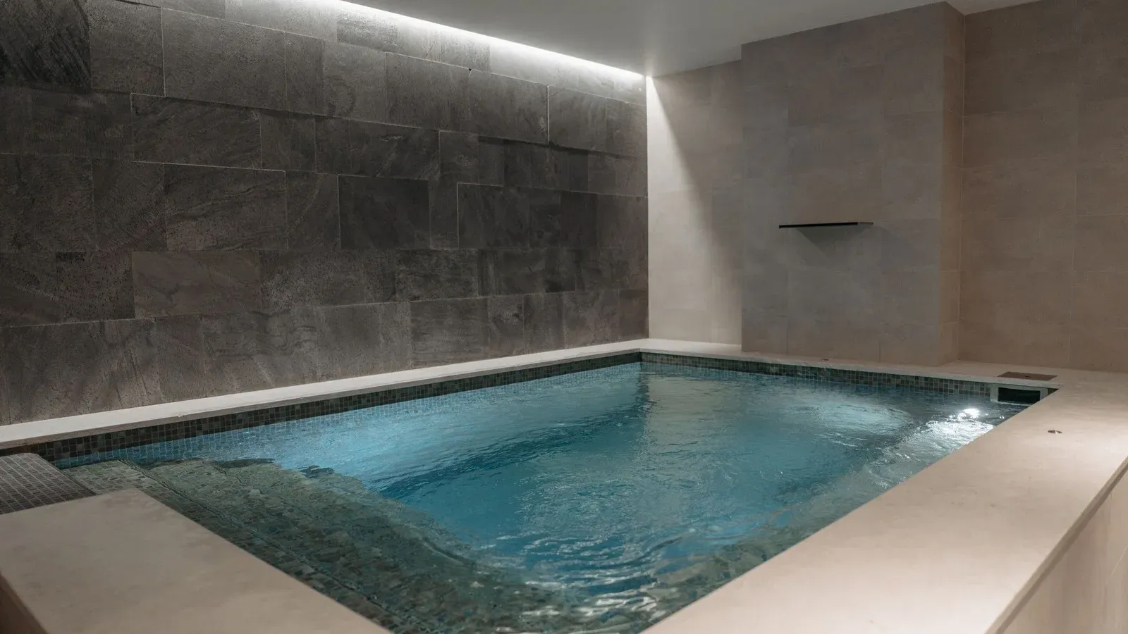 Small indoor plunge pool with stone walls and a wide stone surround