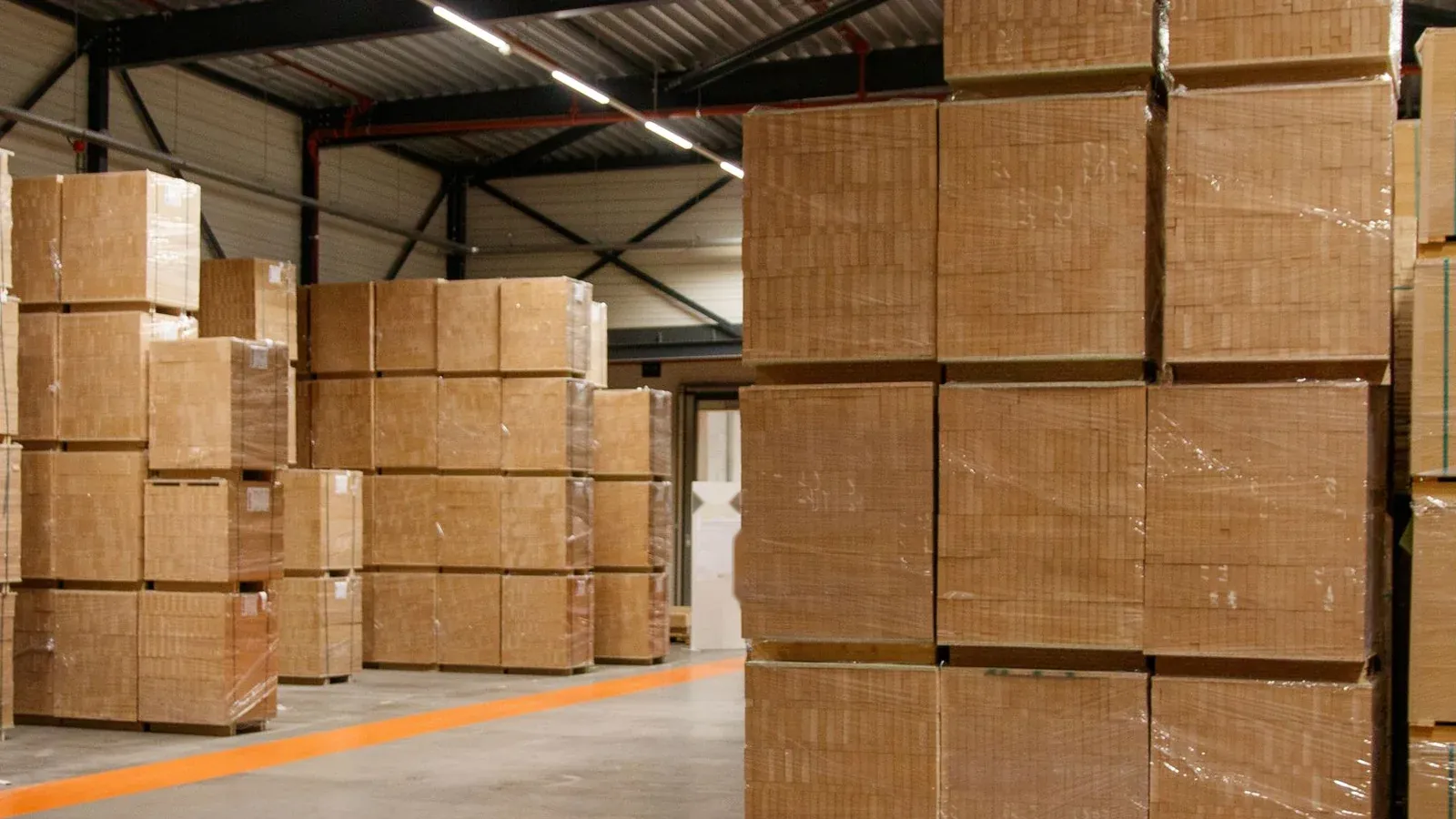 Pallets of stretch-wrapped cartons stacked inside a warehouse
