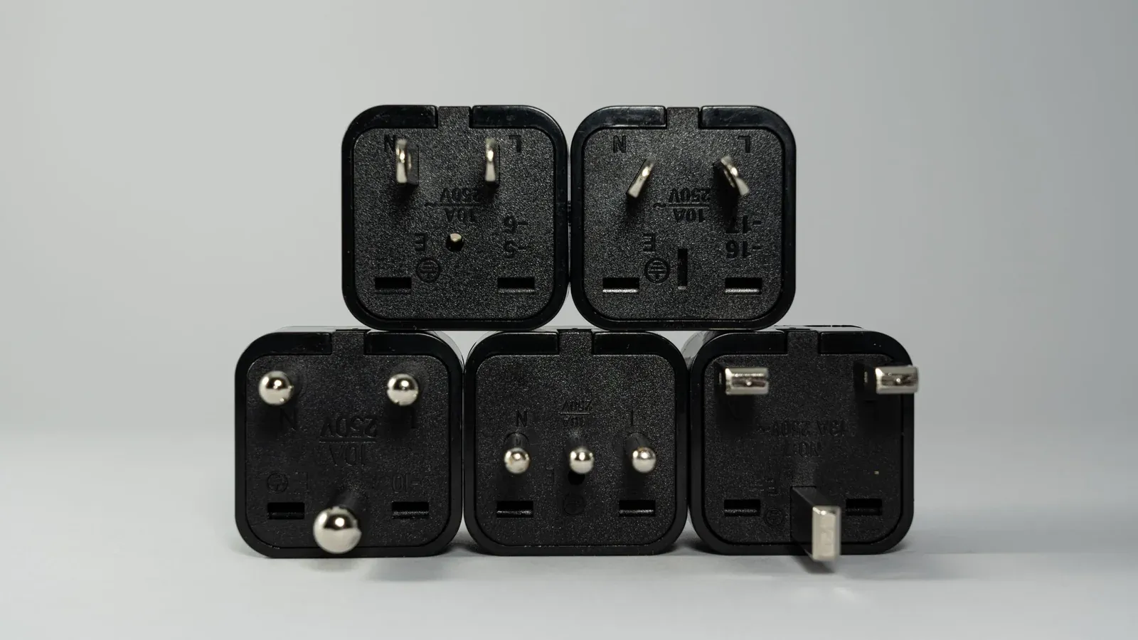 Five travel plug adapters with different pin layouts, including American, Australian and British types