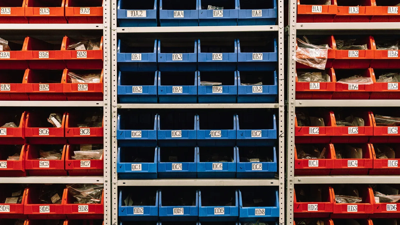 Rows of blue plastic parts bins on a steel rack in a stockroom