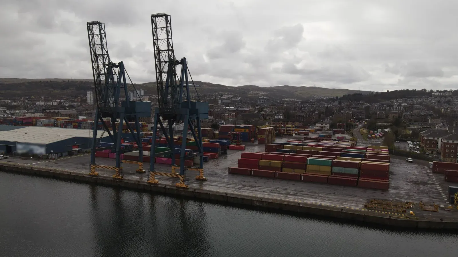 Stacked shipping containers and gantry cranes at a container port terminal