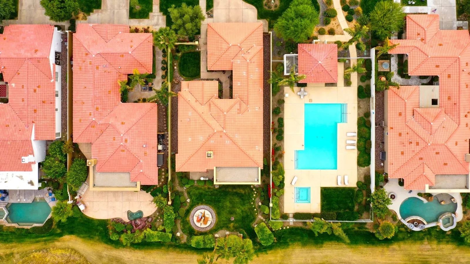 Aerial view of backyard pools of different shapes and sizes in a suburban neighborhood