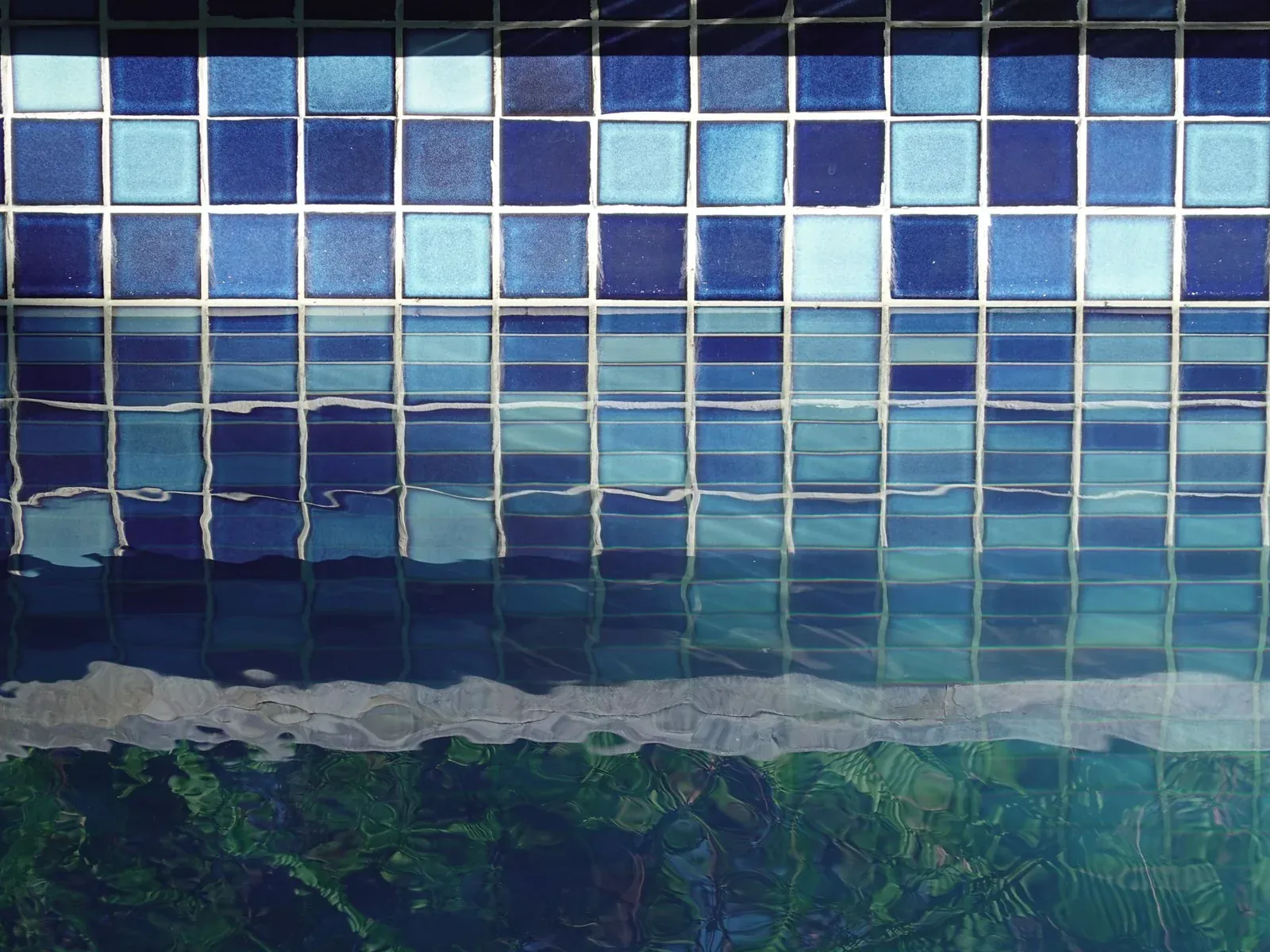 Blue mosaic tile band at a pool's waterline