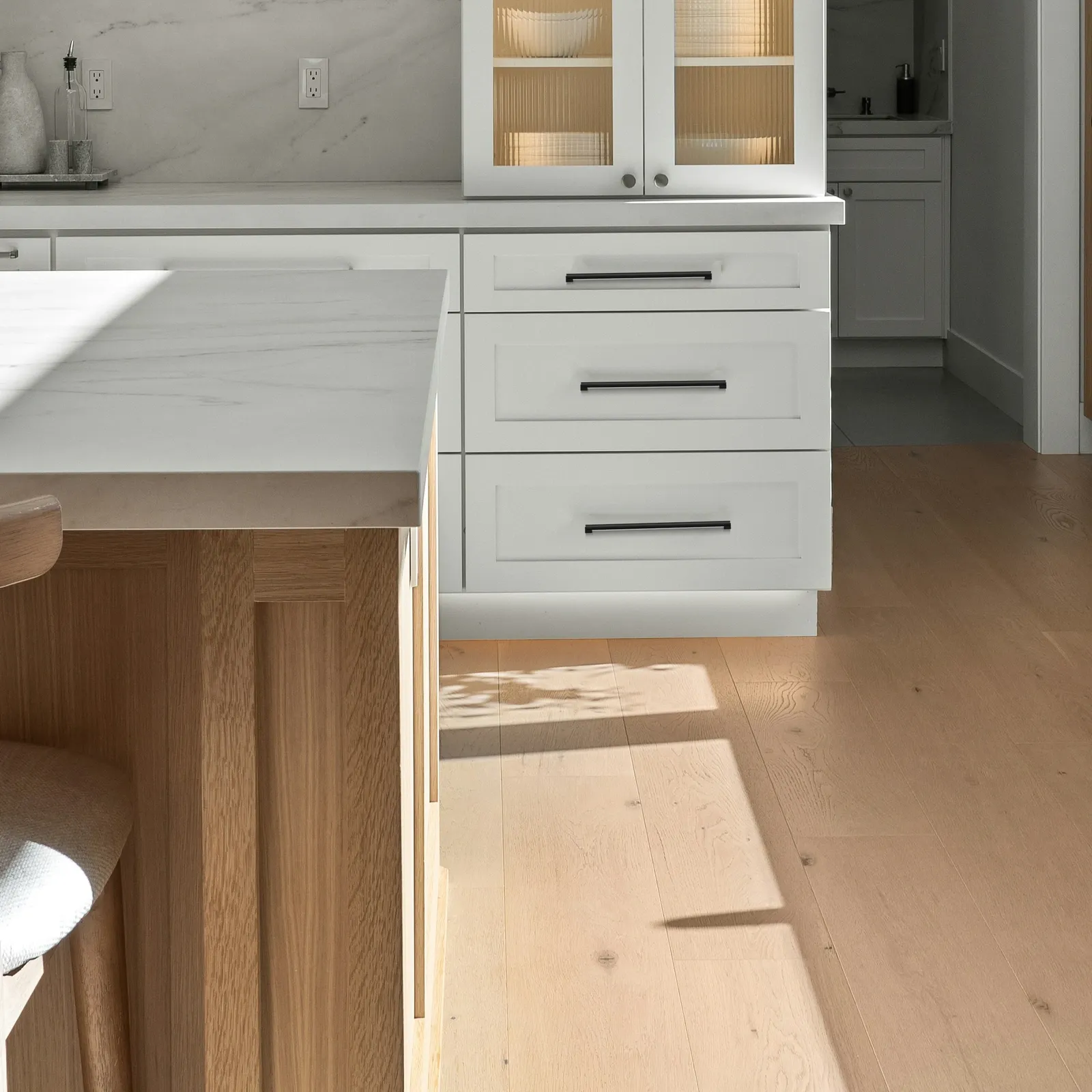 Modern white shaker kitchen with smooth cylindrical matt black aluminum bar pulls on the drawer fronts.