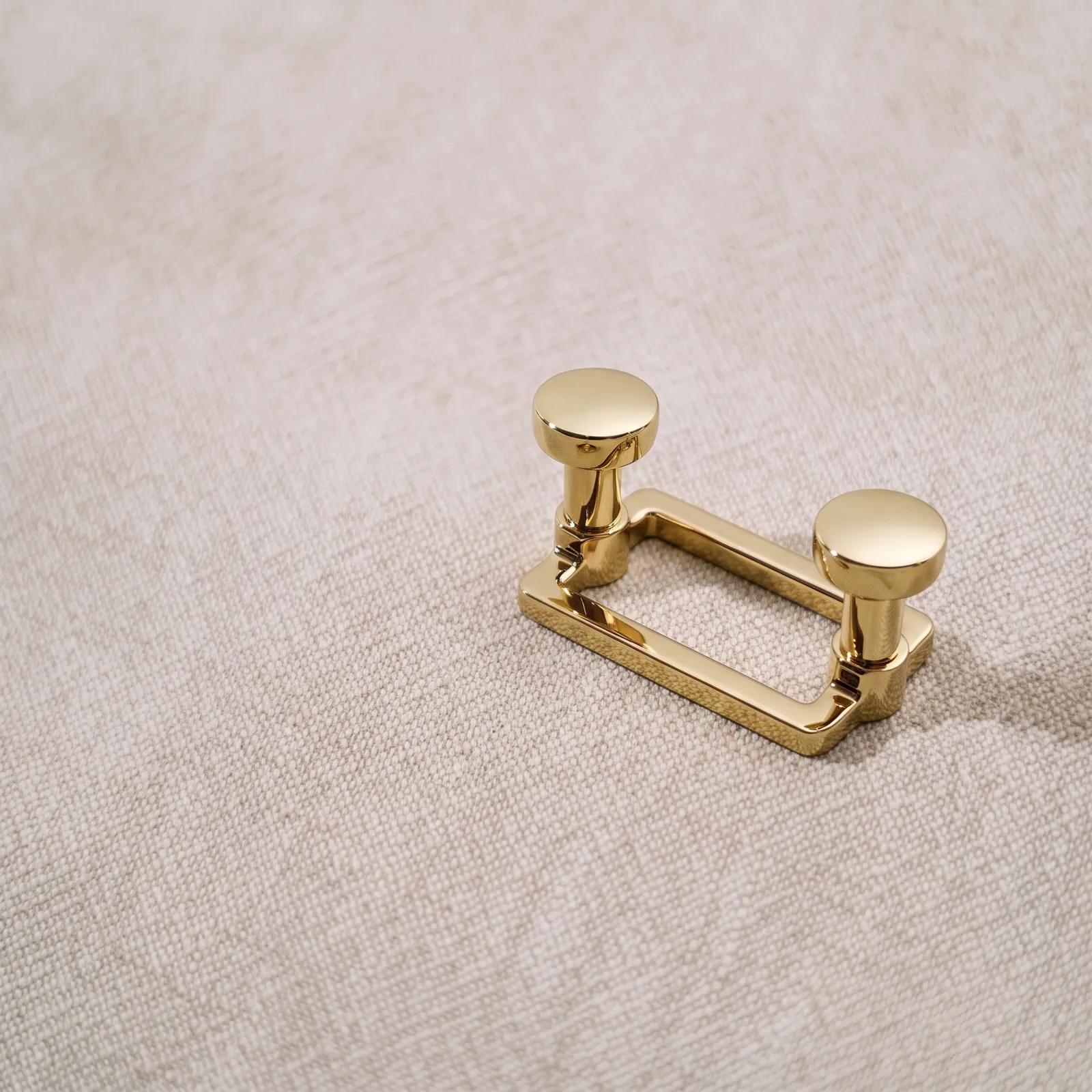 Mirror Gold two-hook rail close up on a linen fabric backdrop, showing the square back plate and round hook heads