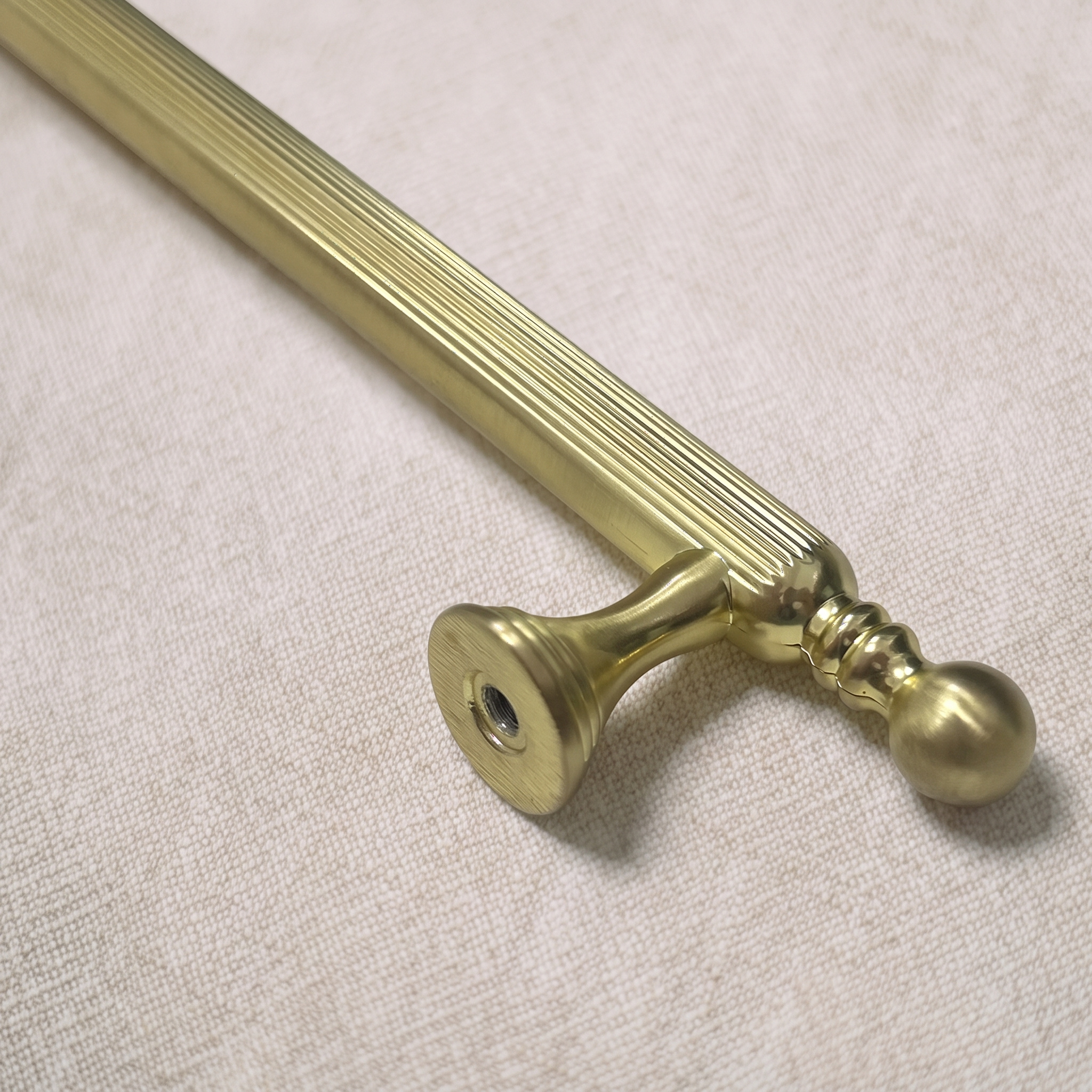 Close view of the stepped round bell foot on the straight-grain zinc cabinet pull, with the mounting socket at its centre