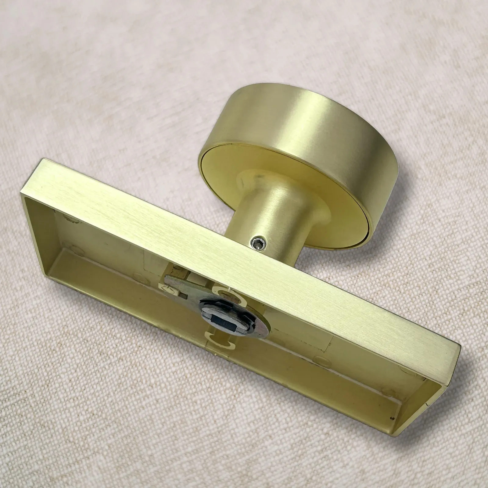 Rear of a brushed gold door knob rose plate showing the mounting posts and turn mechanism