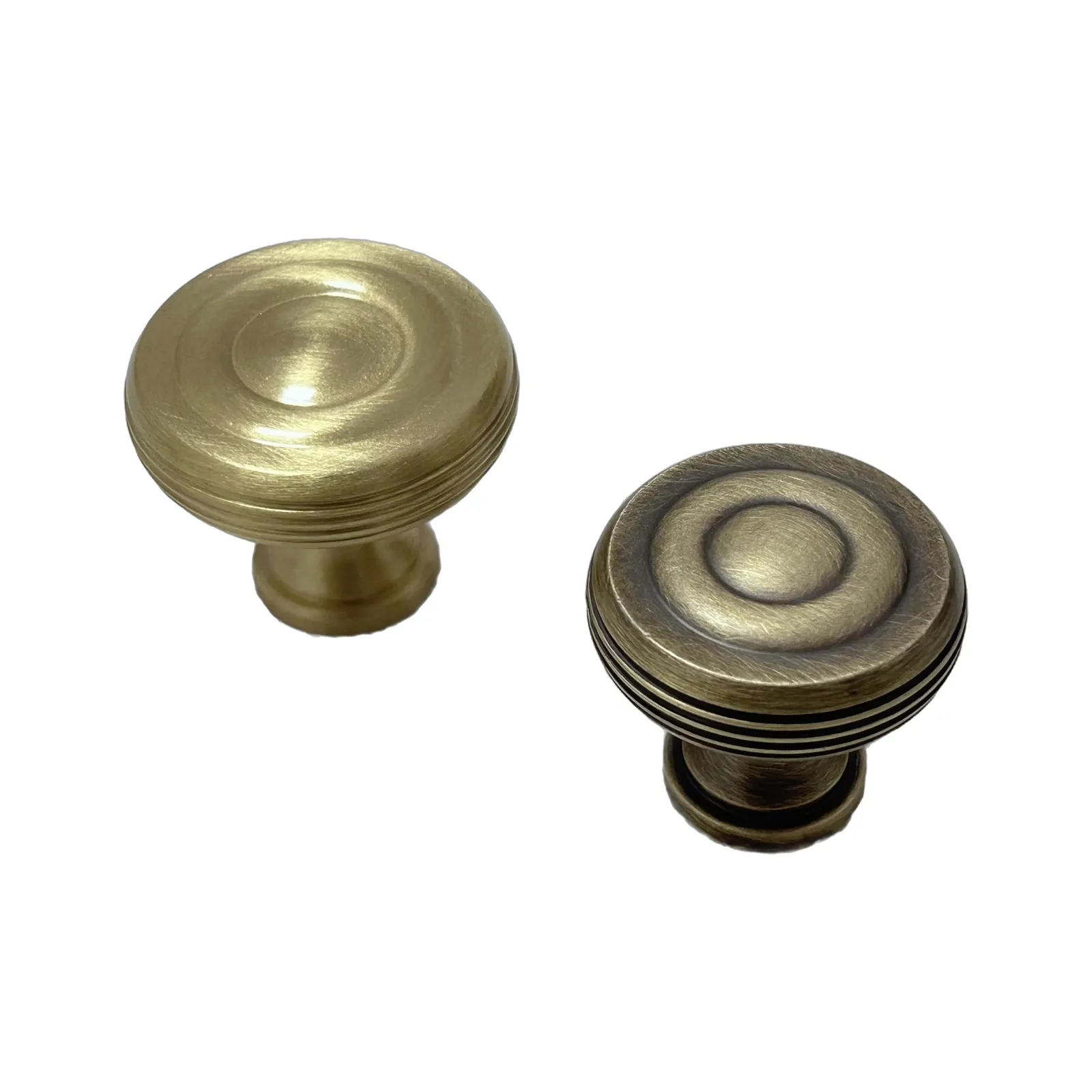 Angled view of a brushed brass knob beside a dark bronze concentric-ring knob, on a white background