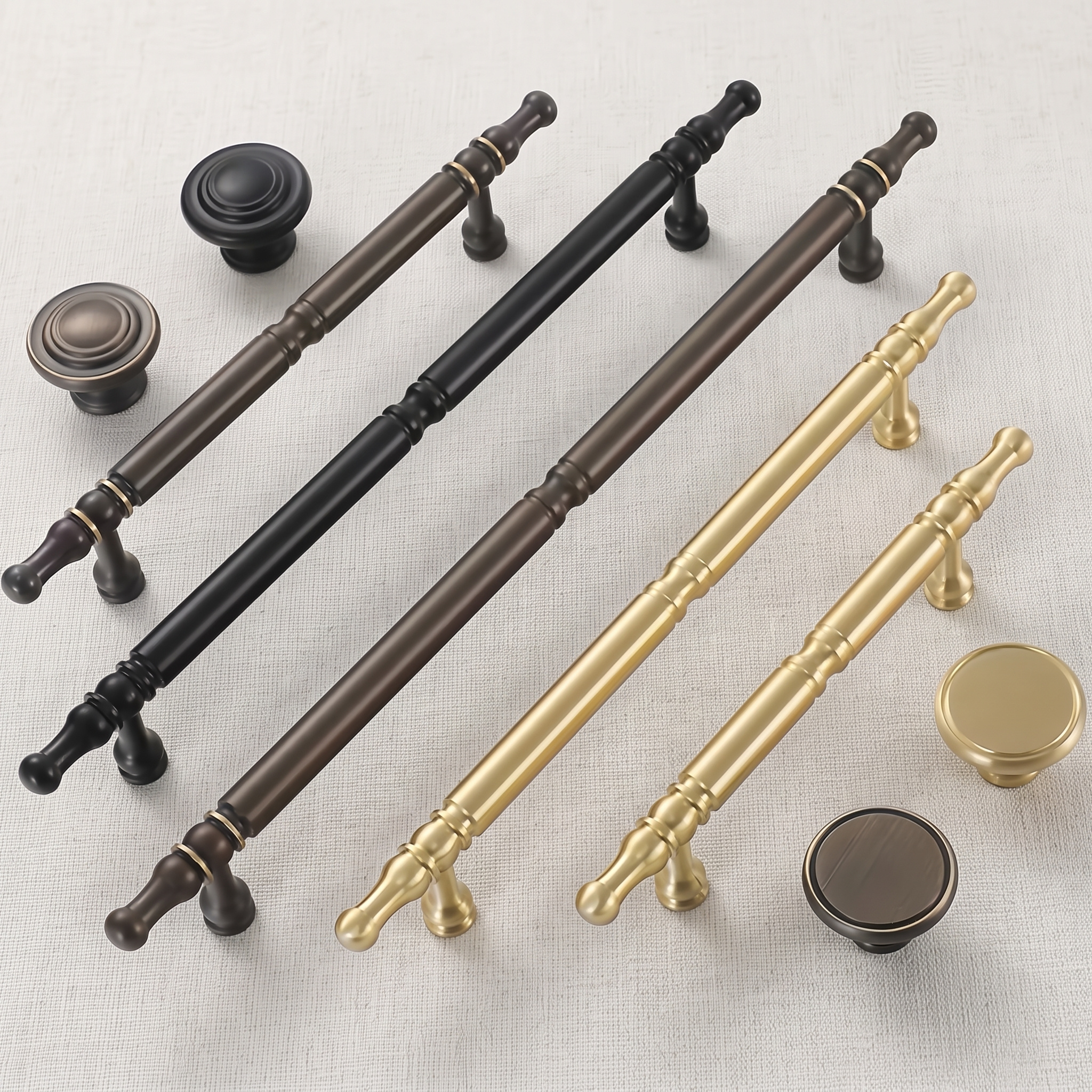 Five turned brass bar pulls and four round knobs in Brass Gold, Coffee Bronze and Matt Black arranged on a pale linen surface