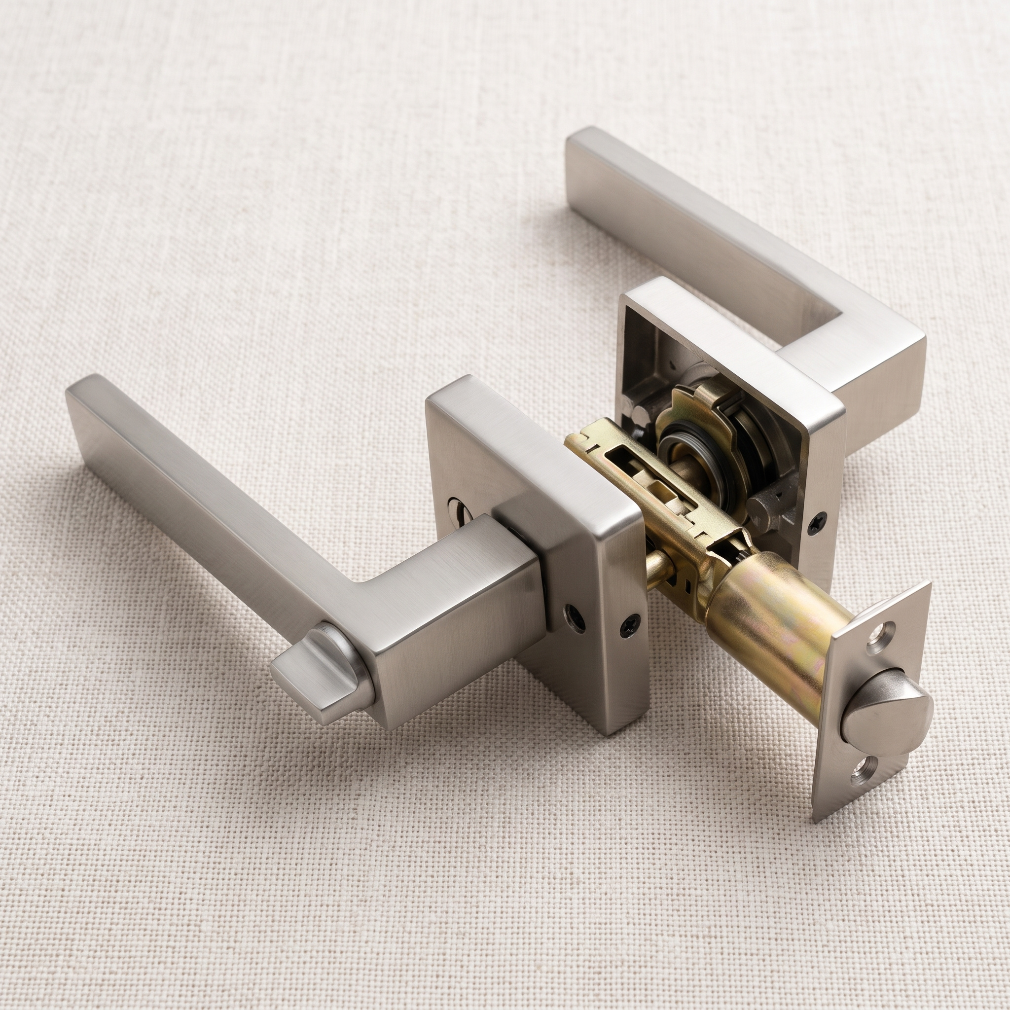 Angled view of a matt silver square-rose keyed door handle lock with its latch, on a pale linen surface