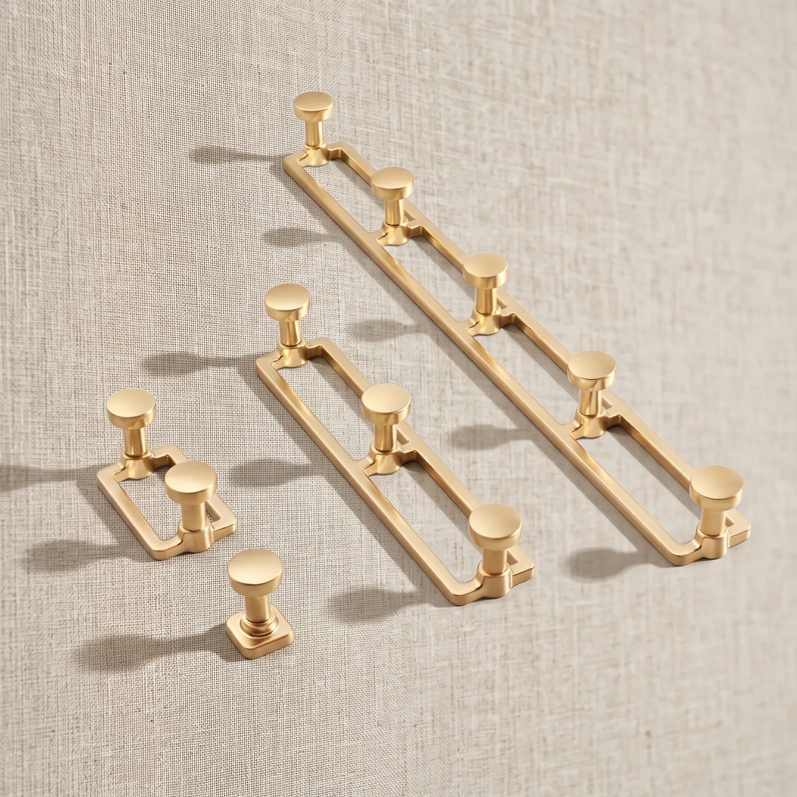 Brass Gold single hook and two, three and five-hook rails arranged on a linen fabric backdrop