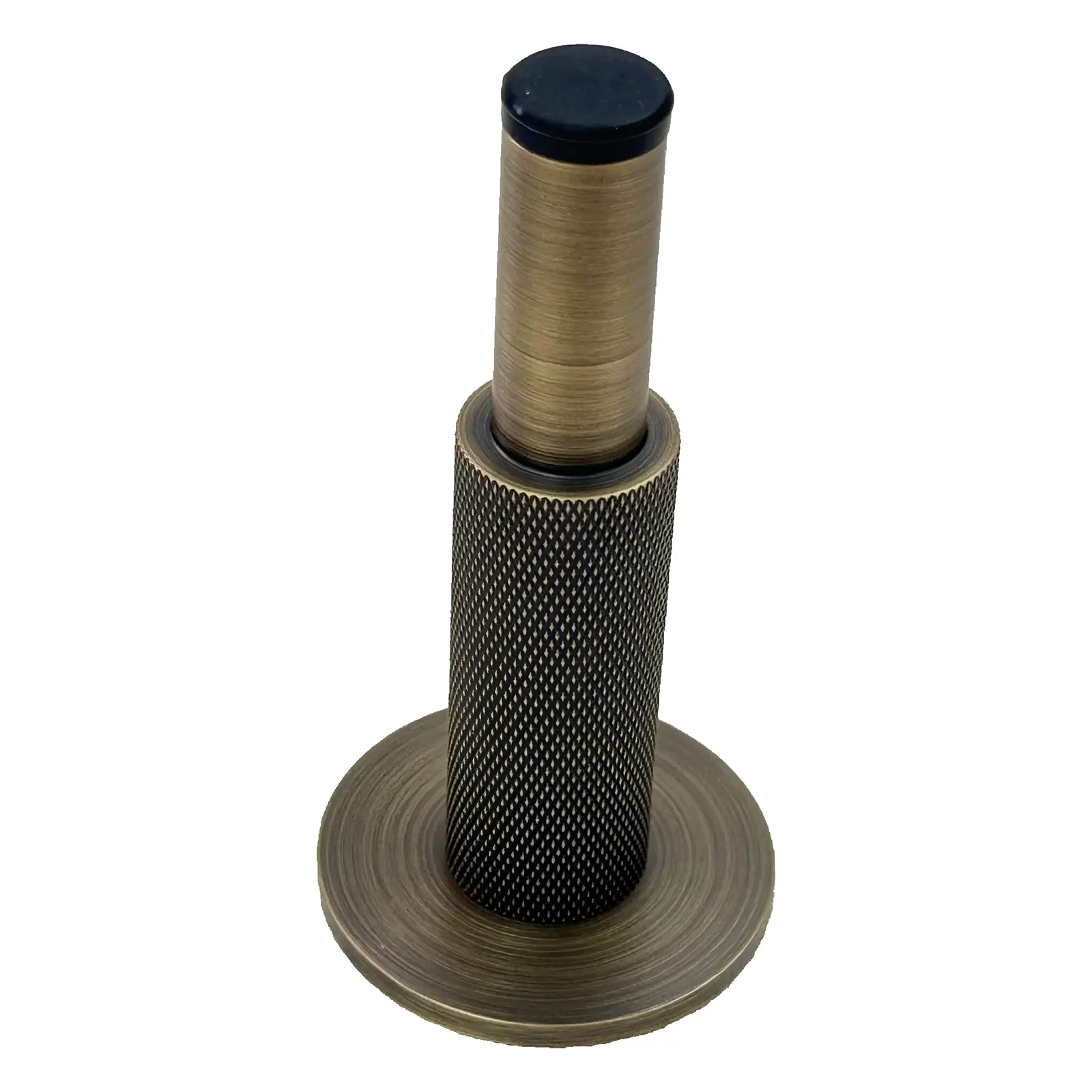 Close view of the aged brass long-stem door stop standing upright on a white background