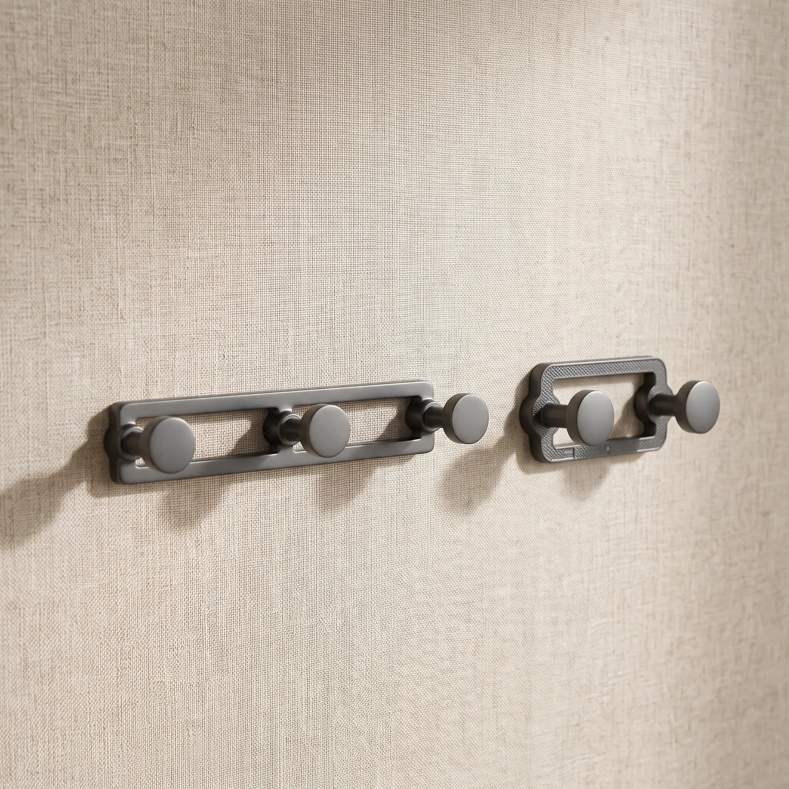 Gunmetal three-hook and two-hook rails mounted on a plastered wall, angled to show the open frames and round hook heads