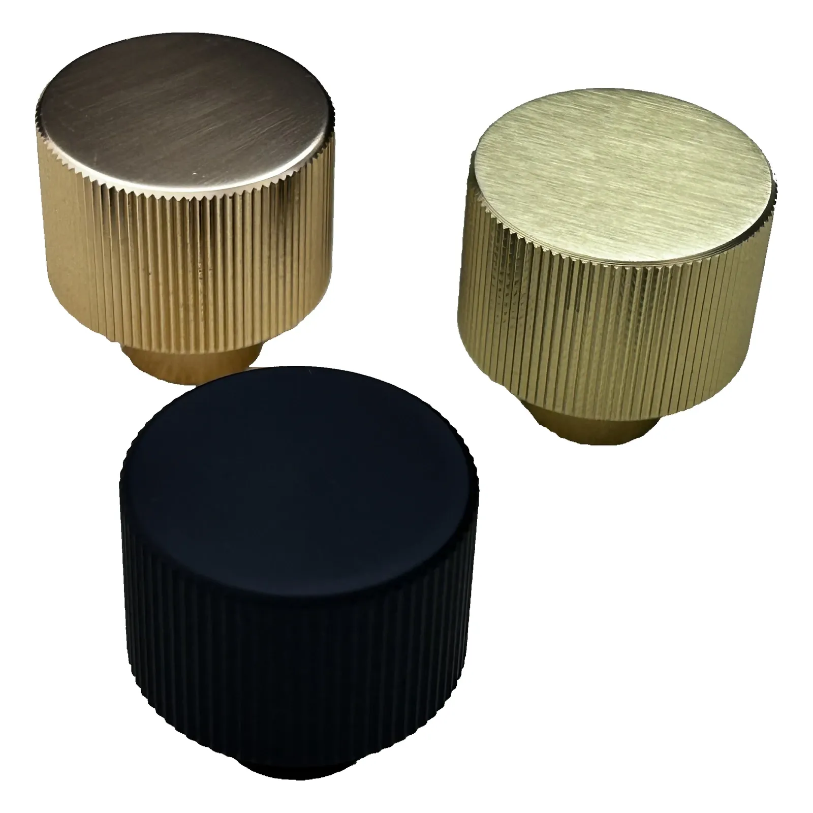 Angled view of three textured round aluminum cabinet knobs in Brush Gold, Champagne Gold, and Matt Black on a white background