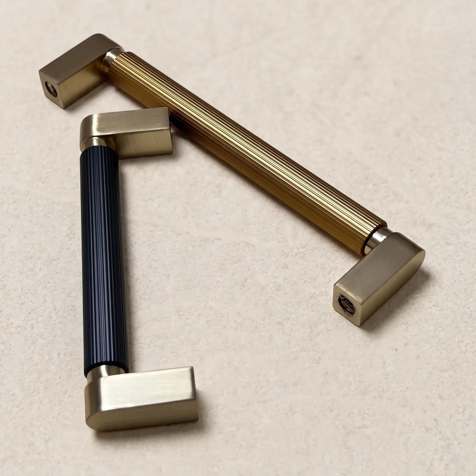 Two color-blocked D-profile pulls arranged at right angles on a cream backdrop, showing the plain end blocks and their fixing holes