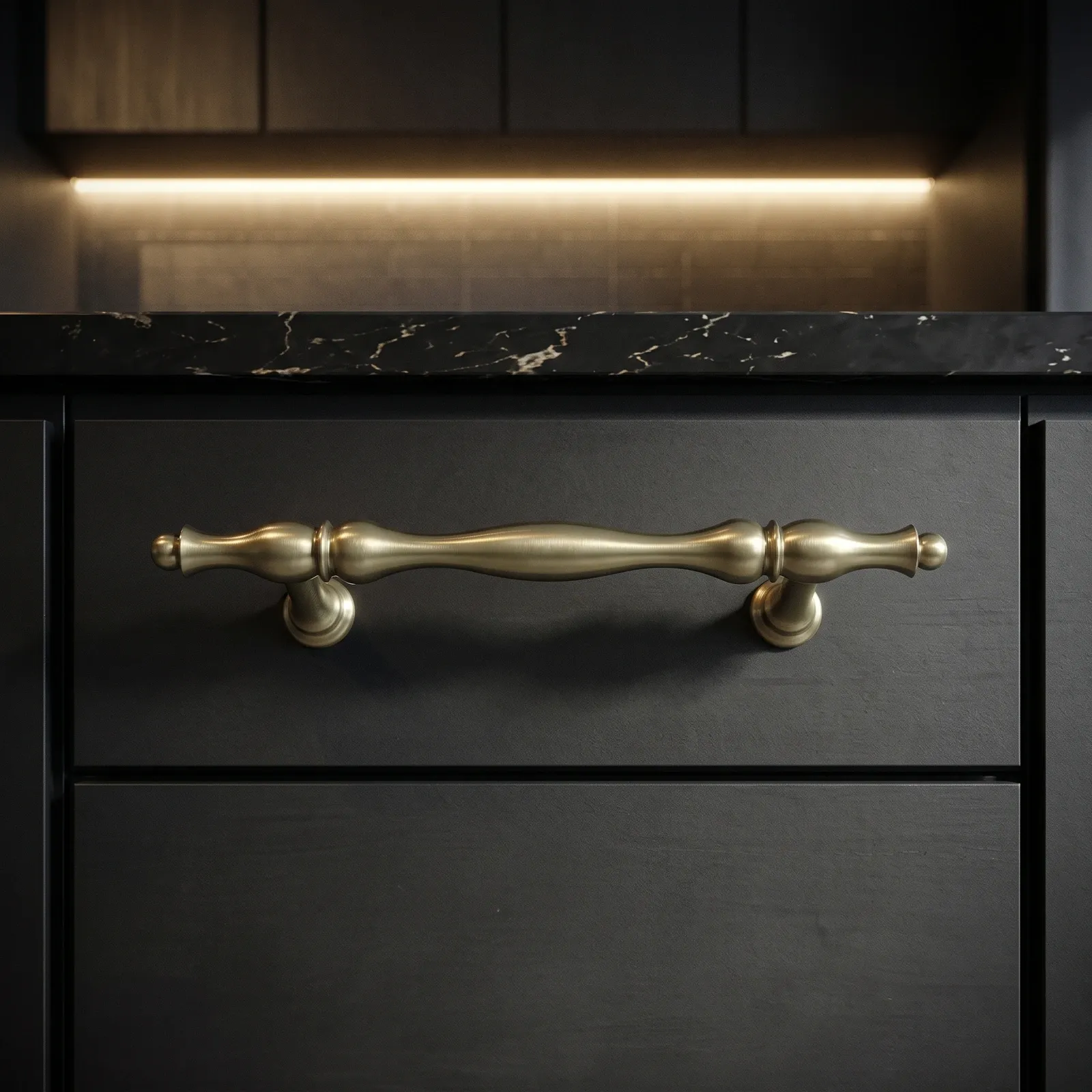 Brass Gold wavy bar pull with ball-tipped ends mounted on a charcoal kitchen drawer front beneath a black marble countertop.